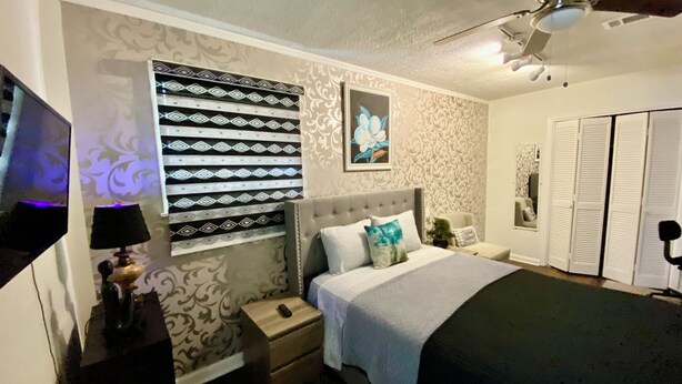 A bedroom with a bed, nightstands, a ceiling fan, and a TV. - Magnolia Suite Vacation Home -Private Entry, Old Canton N. Jackson (Jackson)