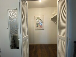 A hallway with a wooden floor, a framed artwork on the wall, and a door with a decorative glass panel.