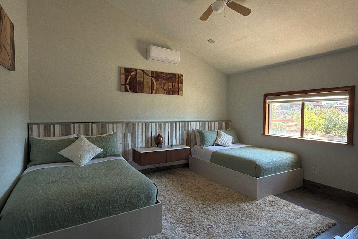 A bedroom with two beds, a ceiling fan, a window, and a rug.