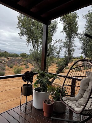A covered outdoor area with a wooden deck, a cushioned chair, and potted plants. - Montevalle Resort and Spa (Valle de Guadalupe)