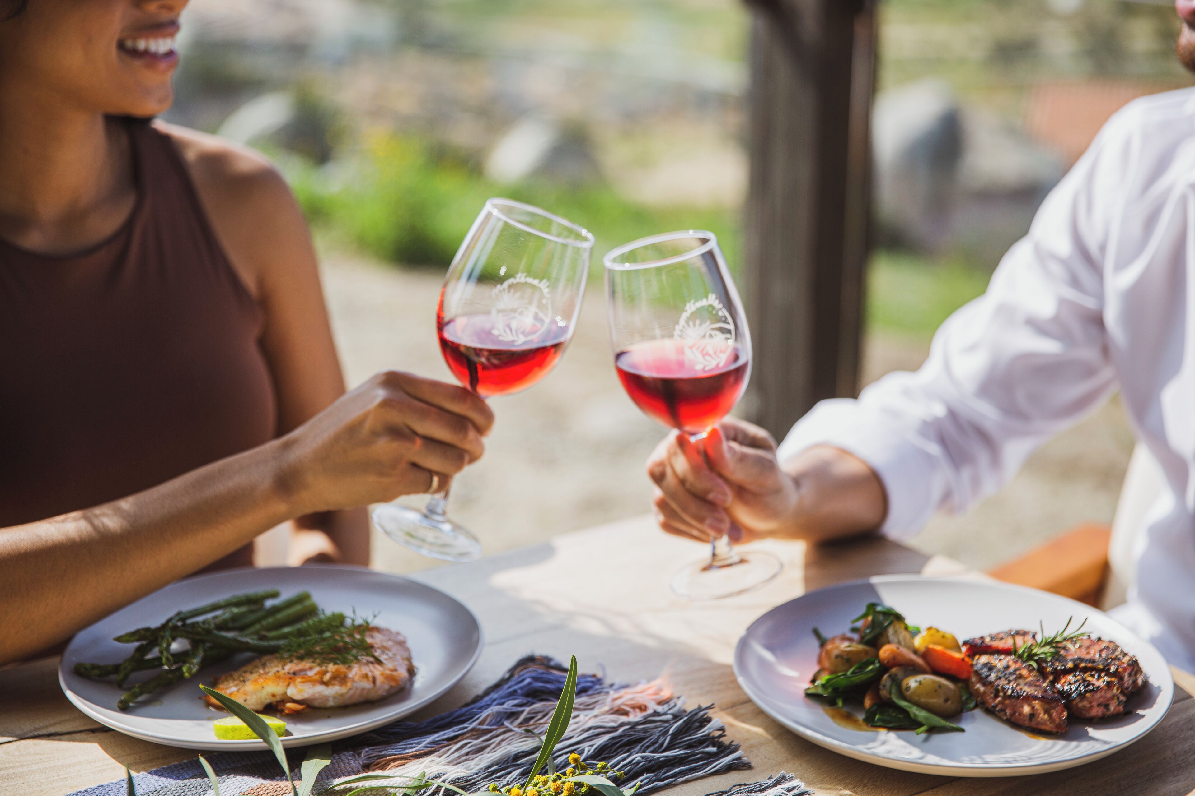 Une table à manger avec des assiettes remplies de nourriture et deux verres à vin.