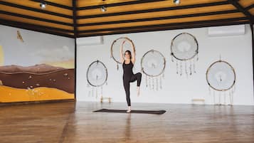 A yoga studio with wooden beams, a mural, and dreamcatchers on the wall.
