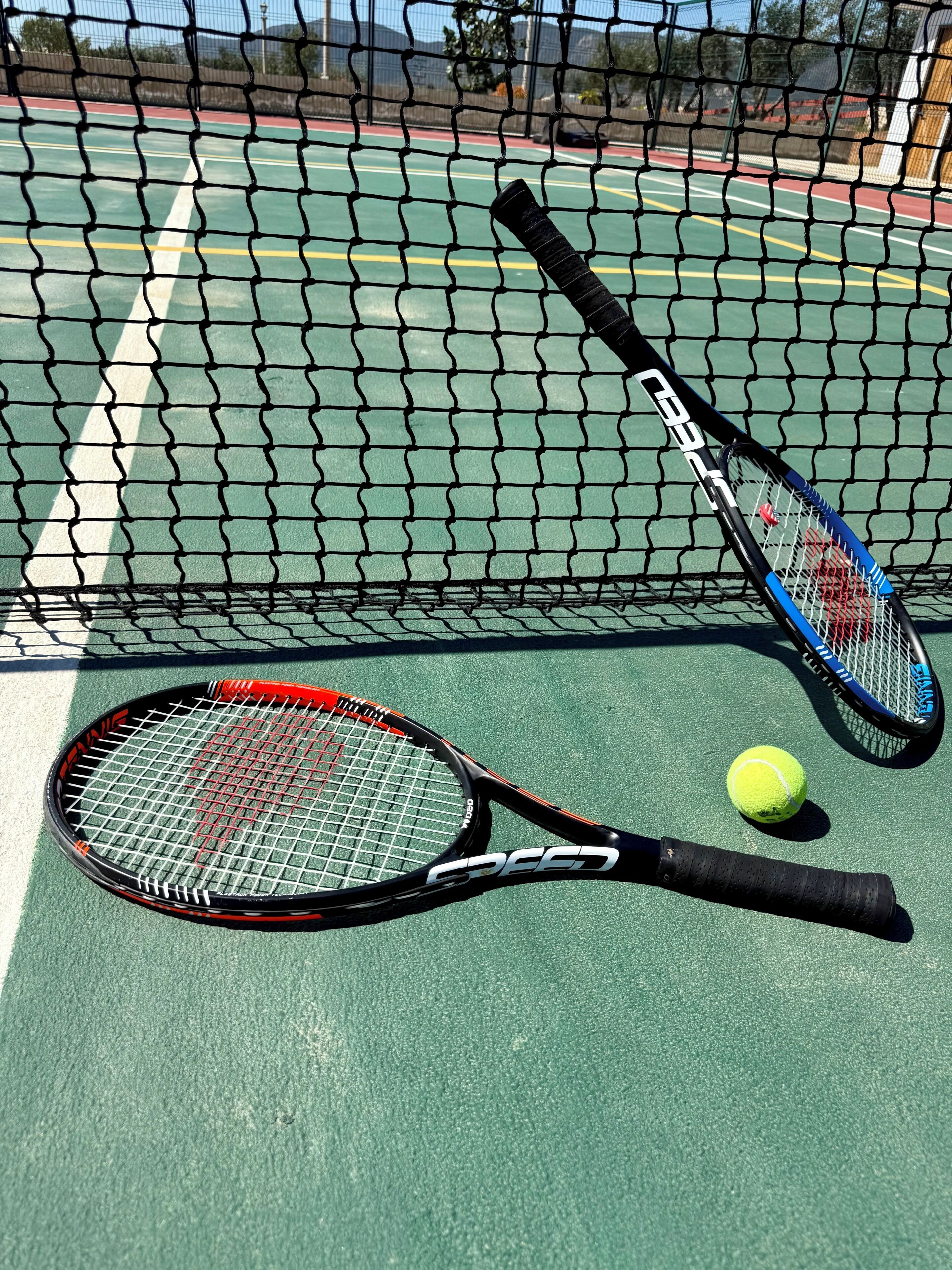 Un campo da tennis con due racchette e una pallina.