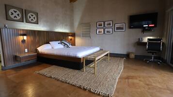 A bedroom with a bed, bedside table, wall-mounted TV, and framed pictures.