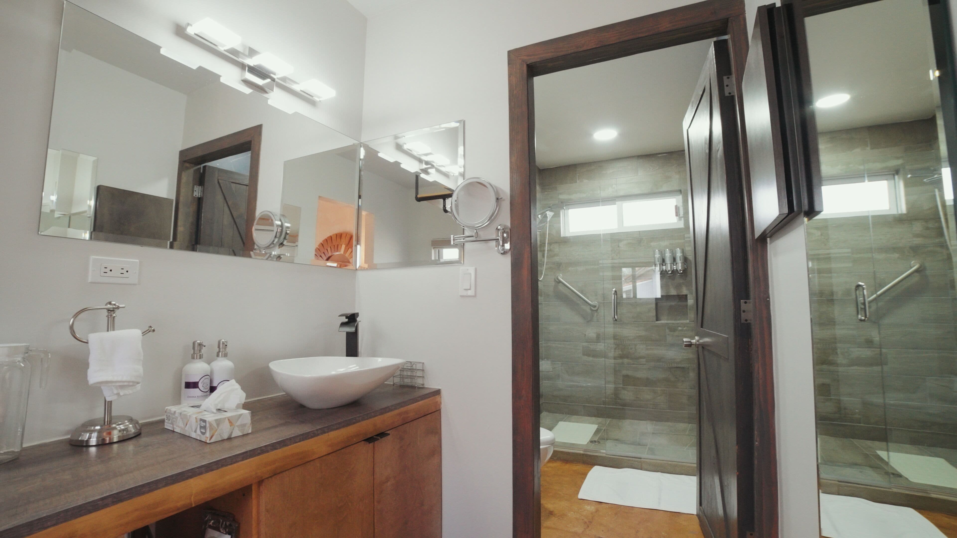 Een moderne badkamer met een grote spiegel, een wastafel en een douchecabine van glas.