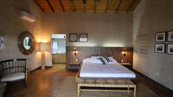 A bedroom with a bed, a chair, a mirror, and wall-mounted lights.