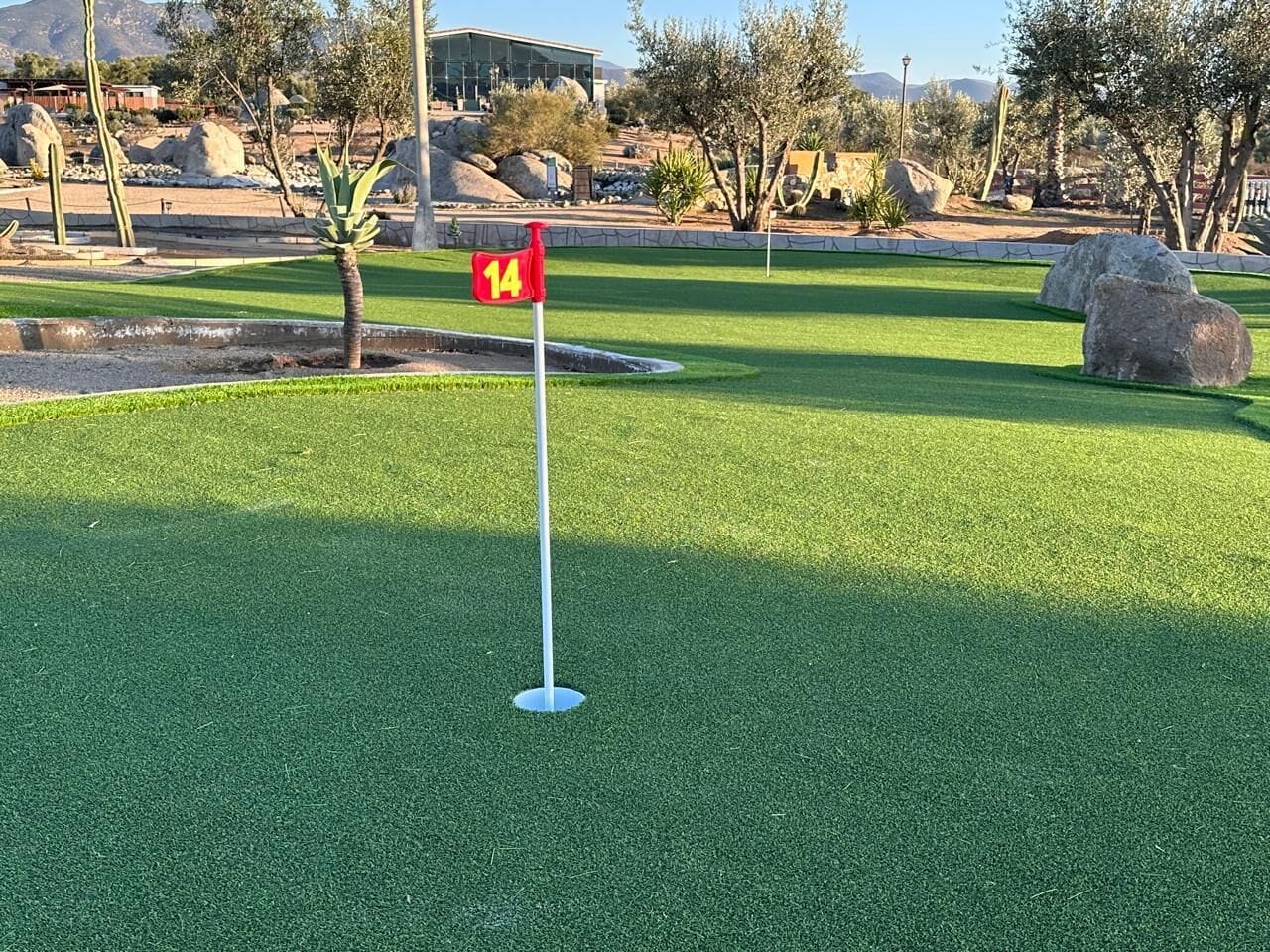 En golfbane med et flag markeret '14' på grønsværd.