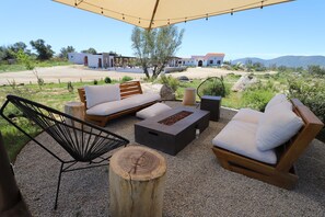 An outdoor seating area with a wooden sofa, a black chair, and a fire pit. - Montevalle Resort and Spa (Valle de Guadalupe)