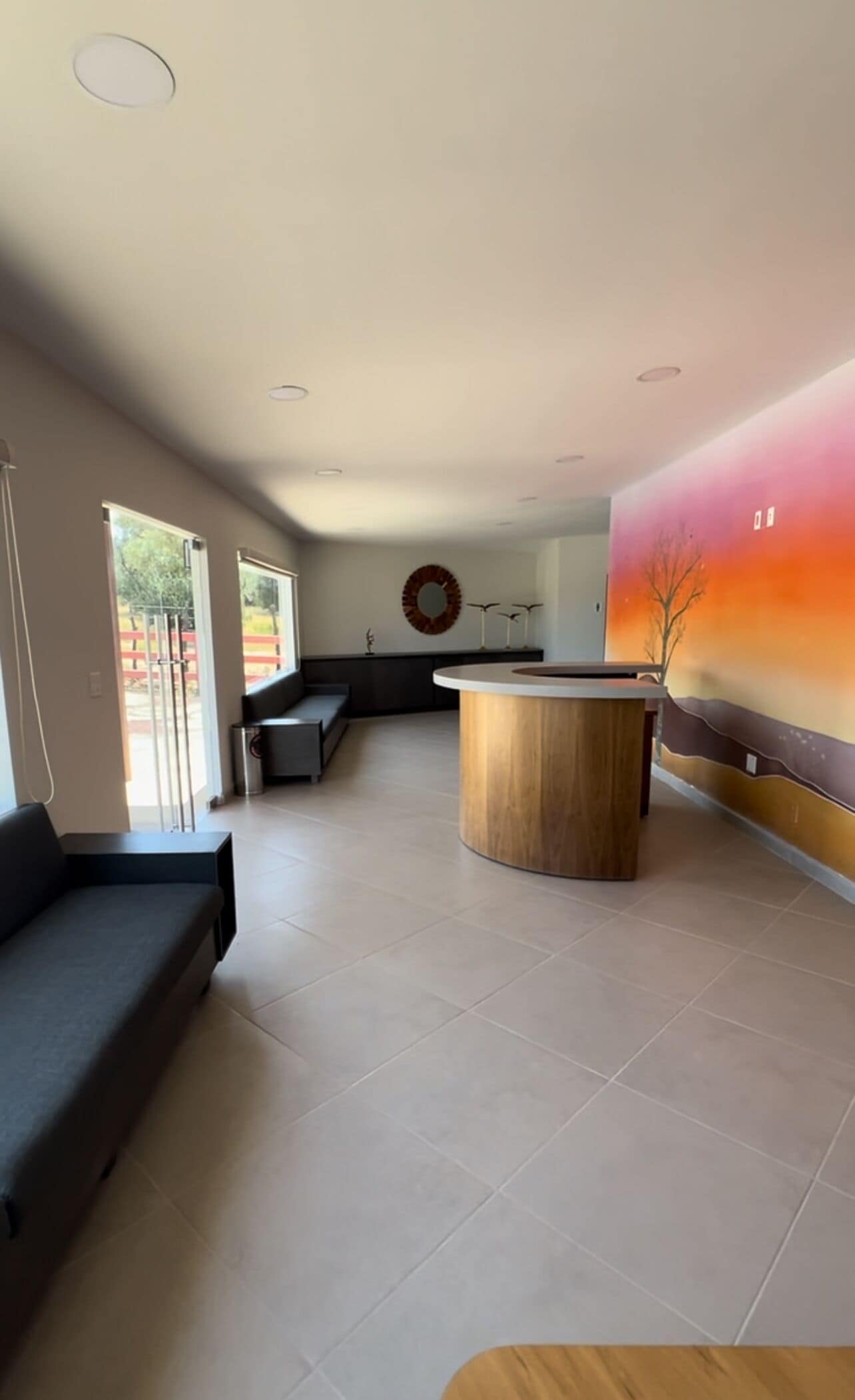 Un interior moderno con un mostrador de recepción, zona de estar y un amplio mural.