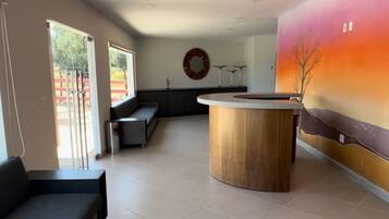 Un interior moderno con un mostrador de recepción, zona de estar y un amplio mural.