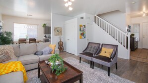 A spacious living room with a sofa, armchairs, a coffee table, and a staircase leading to another level. - Stylish Vacation Home Phoenix - Low Rates NOW! (Phoenix)