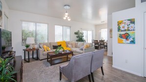 A spacious living room with a sofa, chairs, a coffee table, and a television. - Stylish Vacation Home Phoenix - Low Rates NOW! (Phoenix)