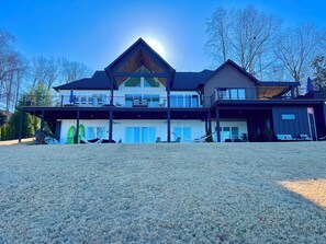 A two-story house with a large deck, a covered porch, and a swimming pool.