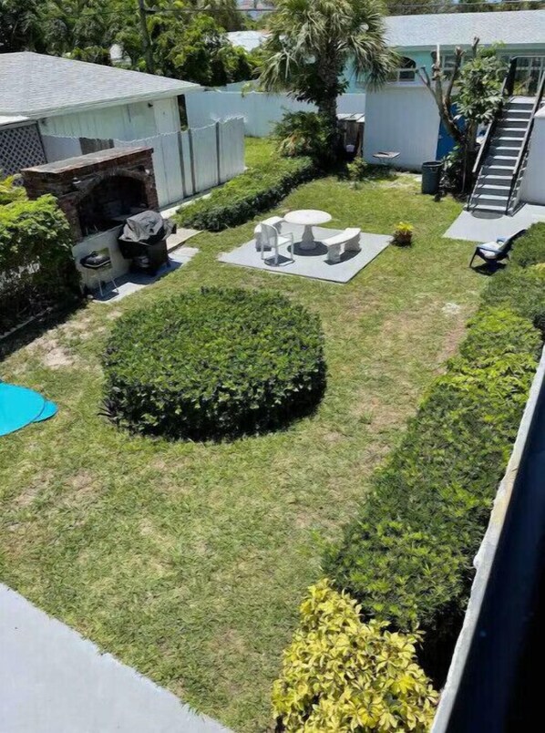 A well-maintained backyard with a circular hedge, a small patio table with chairs, and a pool.