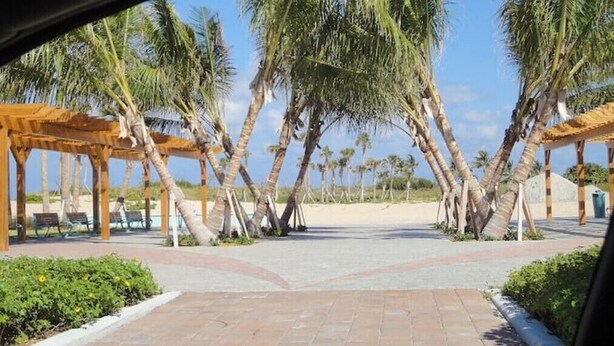 A beachside walkway with palm trees and wooden pergolas. - NEW LISTING - 3 Min Walk-Beach, Hot Tub, Tennis, Wi-Fi (Riviera Beach)