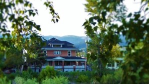 Ein Haus am Flussufer mit einer Veranda und einem Berg im Hintergrund.