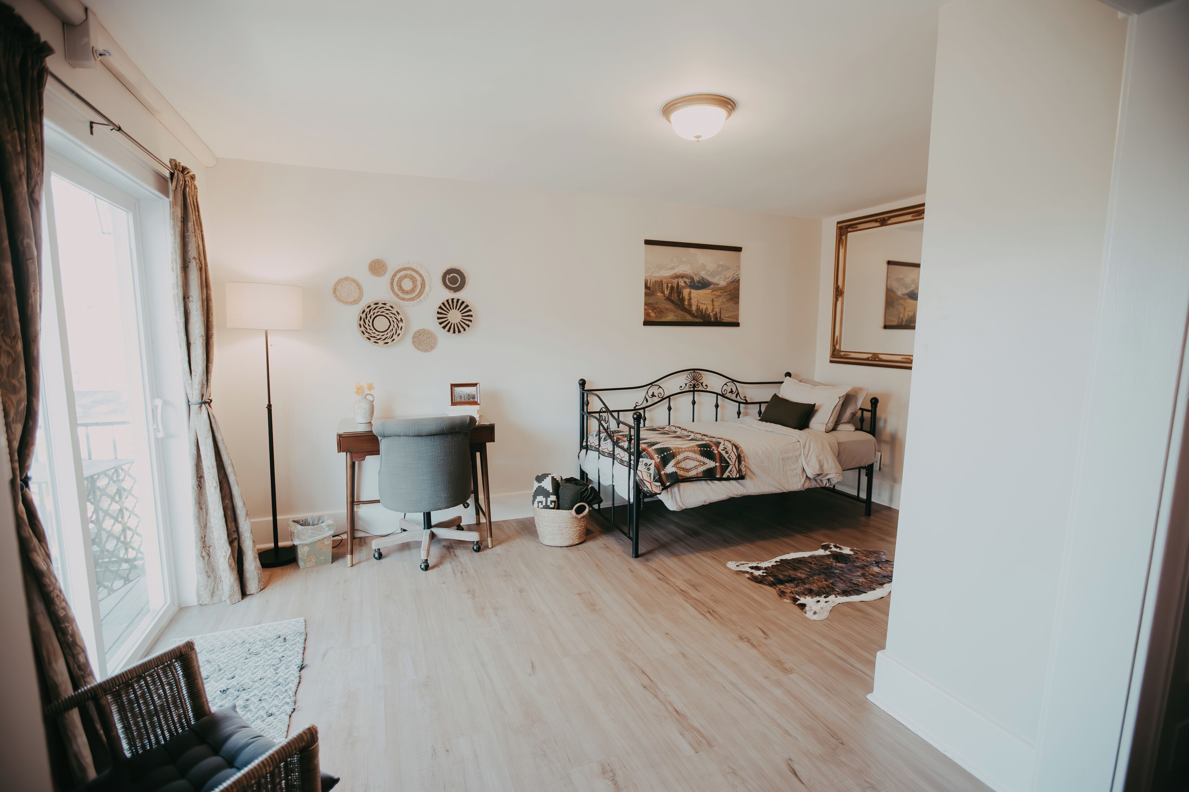 Een slaapkamer met een bed, een bureau, een stoel en een lamp.