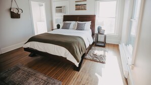 Ein Schlafzimmer mit einem großen Bett, einem Deckenventilator, einem Fenster und Holzboden.