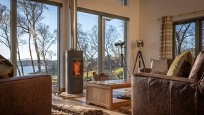 A cozy living room with a fireplace, large windows, and a view of the outdoors. - The View, Duisdale Mor,  Sleat (Isle of Skye)