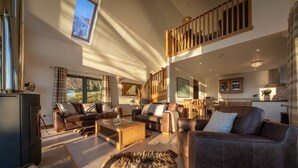 A spacious living room with leather sofas, a coffee table, and a large rug. A dog is lying on the rug. - The View, Duisdale Mor,  Sleat (Isle of Skye)