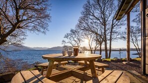 A wooden table and benches on a deck with a view of a lake and mountains. - The View, Duisdale Mor,  Sleat (Isle of Skye)
