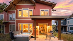 Una casa a due piani con patio coperto, vasca idromassaggio e zona barbecue.