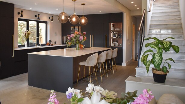A modern kitchen with a central island, bar stools, pendant lighting, and a staircase leading to an upper level. - 4 Bedroom House in Sotogrande Alto (San Roque)