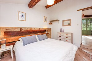 Une chambre à coucher avec une tête de lit en bois, un lit avec une literie blanche, une table de chevet avec une lampe, une commode et un miroir.