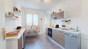 Une cuisine moderne équipée d’un lave-vaisselle, d’un four et d’un petit coin repas avec une table et des chaises.