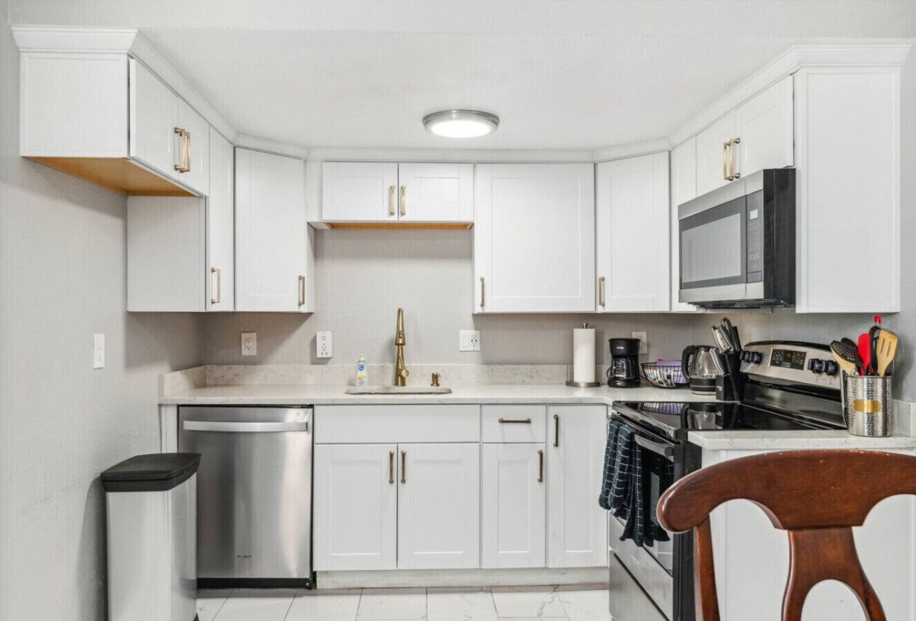 A modern kitchen with white cabinetry, stainless steel appliances, and a central island.