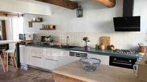 Een moderne keuken met witte kasten, een houten eiland en een zwarte afzuigkap.