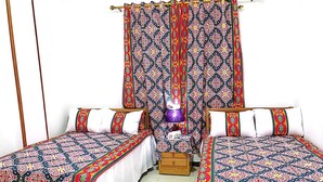 A room with two single beds, a wooden nightstand, a purple lamp, and patterned curtains. - 9 SIDY GABAR ST NAZLET EL SMAN HARAM GIZA (Nazlet el sman-Haram)