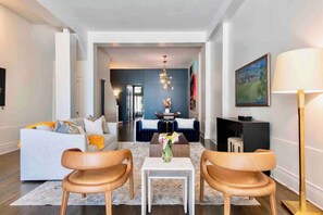 En moderne stue med sofa, to læderstole, et sofabord og en lysekrone.