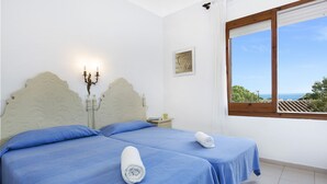 Een slaapkamer met twee bedden, een nachtkastje, een kandelaar en een raam met uitzicht.