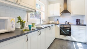 Een moderne keuken met witte kasten, een inbouwoven en een raam dat voor natuurlijk licht zorgt.