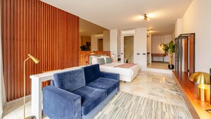 A modern living room with a blue sofa, a white couch, and a wooden accent wall. - Charming Studio in Bolhão Market (Oporto)