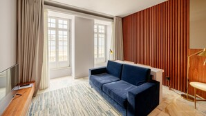 A modern room with a blue sofa, a TV, and a wooden accent wall. - Charming Studio in Bolhão Market (Oporto)