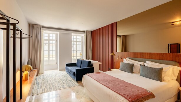 A hotel room with a bed, a sofa, a desk, a lamp, and a window. - Charming Studio in Bolhão Market (Oporto)