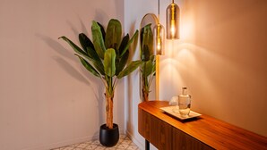 A potted plant, a wooden console table with a bottle, and a wall-mounted light fixture.