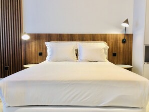 Relax in a serene space with a large bed, wood headboard, and wall-mounted lighting.