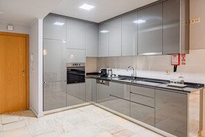 A modern kitchen with stainless steel appliances, a built-in oven, and a sink. - Jewel Studio in Bolhão Market (Oporto)