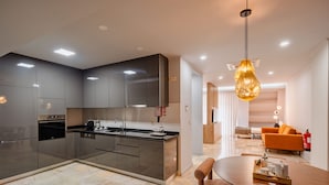 Una cocina moderna con una isla central, electrodomésticos integrados y un comedor con una mesa redonda y sillas.