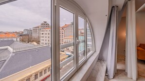 Una habitación con un ventanal amplio, vistas a edificios, un sofá y una cortina.