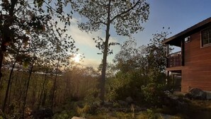 Une cabane en bois avec une terrasse et une vue sur le coucher de soleil.