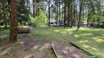 Ett skogsområde med ett picknickbord och en lekställning i trä.