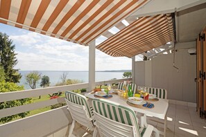 Une terrasse avec une table dressée pour le dîner, donnant sur une étendue d’eau.
