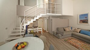 A modern living room with a staircase, a dining area, and a sofa set. - Il Melagrano A11 by Wonderful Italy (Padenghe sul Garda)