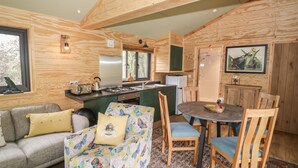 A cozy cabin interior with a living area, a dining table, and a kitchen. - Dragonfly (Rugby)