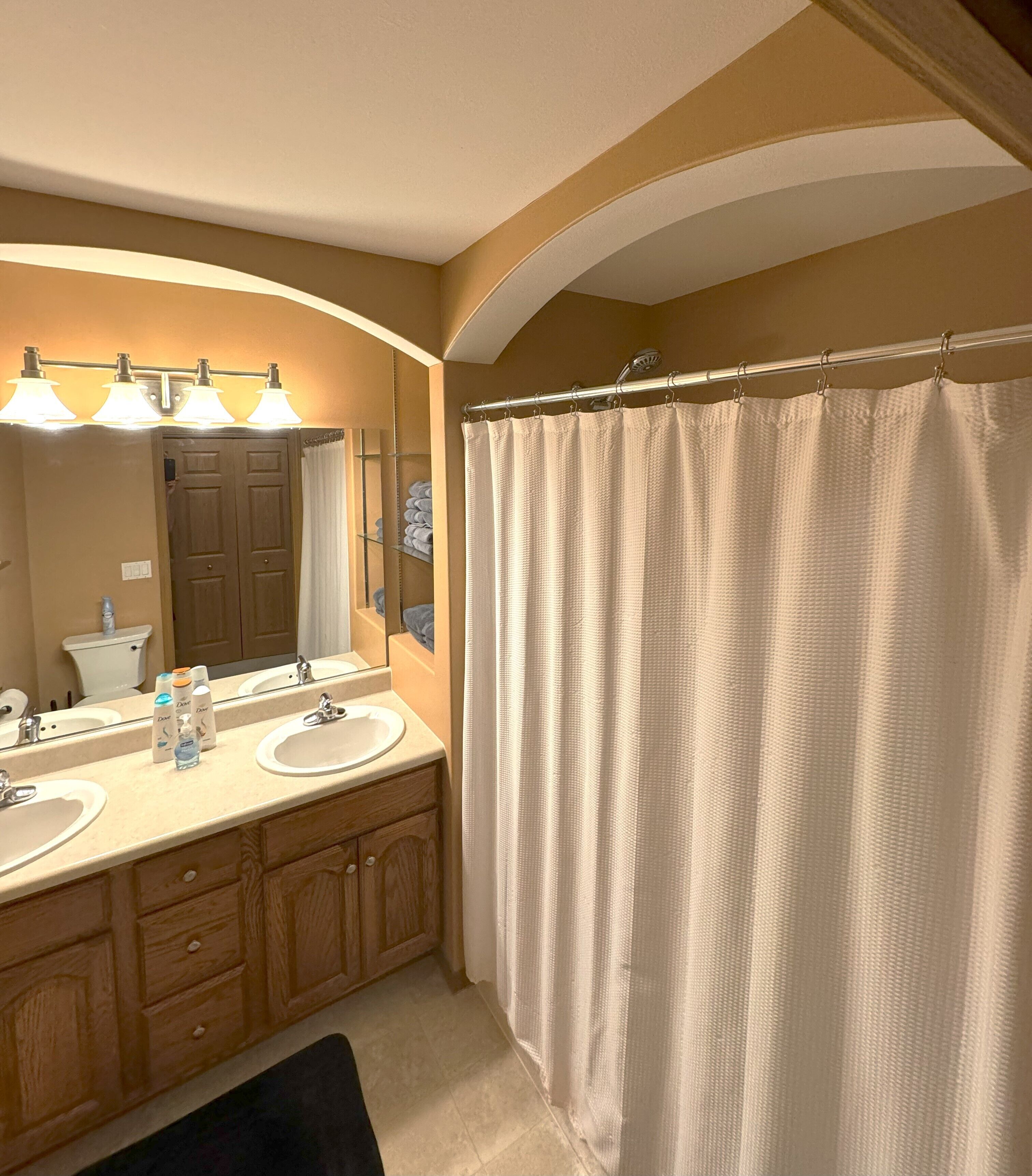 Une salle de bain avec deux lavabos, un miroir et un rideau de douche.