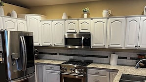 A modern kitchen with white cabinetry, stainless steel appliances, and a granite countertop.